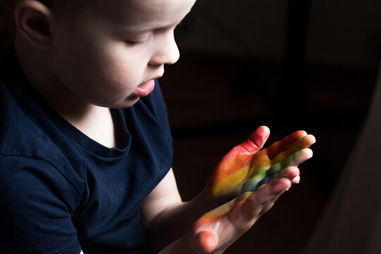 a little boy shows his rainbow-colored hands. the child drew a rainbow on his hands, the baby looks at the palms