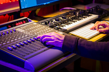 close up male sound engineer hand mixing music on digital audio mixing board in sound studio. music...
