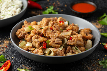 Stir fry chinese salt and pepper chicken with rice in grey bowl