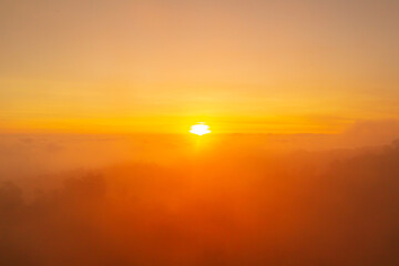 First light of the day at sunrise time in the morning over clouds fog or mist on the mountain forest.
