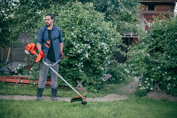 A man mows the grass with a hand mower in the garden