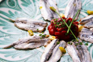 Plate of anchovies with roasted peppers and piparras. Traditional Spanish tapa served on a plate of the Andalusian culture.