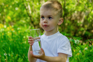 The child drinks clean water in summer. Selective focus.