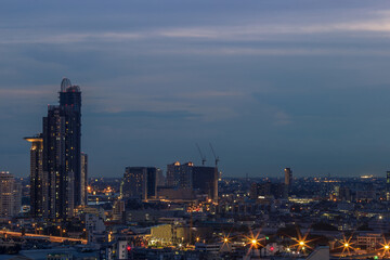 Obraz premium The high angle background of the city view with the secret light of the evening, blurring of night lights, showing the distribution of condominiums, dense homes in the capital community