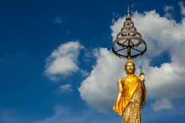 Fototapeta na wymiar The standing Buddha statue in The attitude of Buddha giving boons with blue sky background at Wat Amara Wararam Temple, Bangkok Thailand