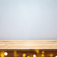 Empty wooden table over gray wall background with festive bokeh lights.  Interior mock up for design and product display.