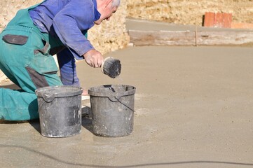 The mason pours fresh concrete poured on the foundation wall