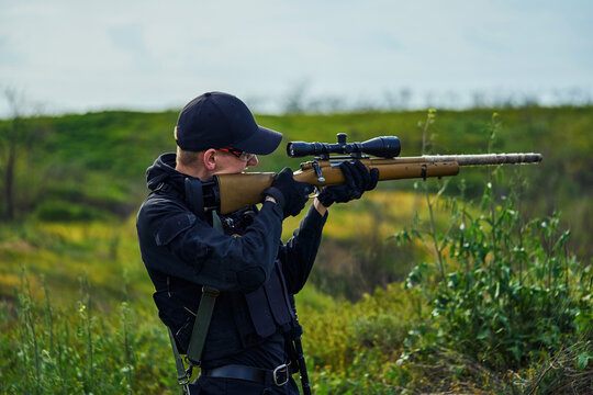 Police sniper aiming at the scope of his rifle