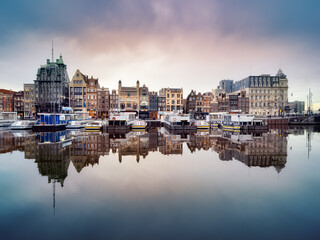 Reflection of historic canal houses and tourist canal boats in the Damrak canal in Amsterdam. © Nik