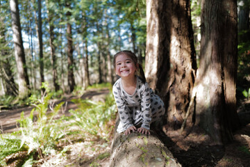 Naklejka na ściany i meble A girl climbing to a log in a forest
