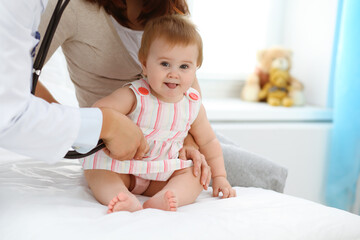 Fototapeta premium Happy smiling girl-child at usual medical inspection. Doctor and female toddler patient in the clinic. Medicine concept