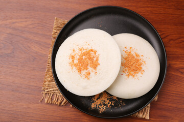 Thatte idli or Plate idly with sambar coconut chutney, chutney podi popular breakfast of Kerala South India Sri Lanka. Healthy steamed rice cakes steaming fermented batter black lentils and rice.