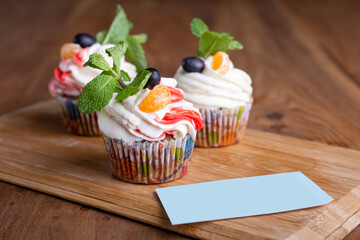 three cupcakes with a business card template on a wooden stand