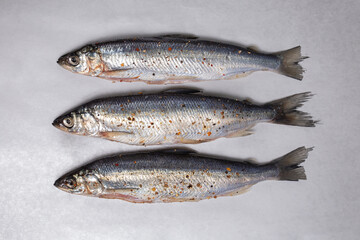 three fish in spices on a gray background