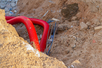 Laying an insulating plastic pipe with an electric cable underground during the construction of a...
