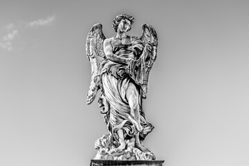 Fototapeta na wymiar Medieval outdoor stone statue of an Angel with whips by Lazzaro Morelli on Sant'Angelo Bridge in Rome, Lazio region, Italy