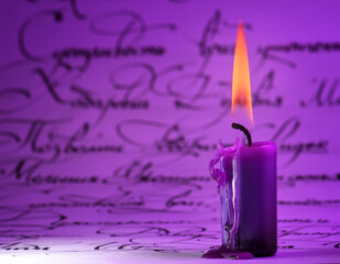 purple candle on a background of manuscripts.