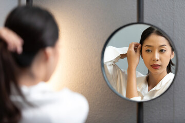 beautiful woman looking on reflection in the mirror and checking her hair