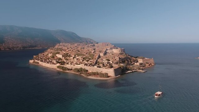 Spinalonga Greek island landscape drone shot with empty houses. Aerial top day view of famous deserted leper colony with fortifications, currently a tourist attraction, in north-eastern Crete. 