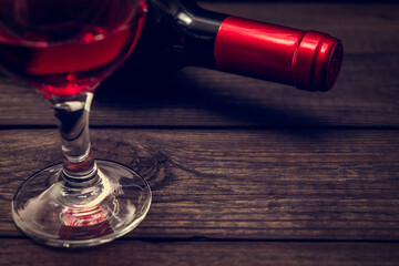 Bottle of red wine with a glass of red wine on an old wooden table. Close up view