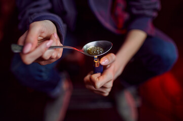Drug addict with spoon and fire prepares dose