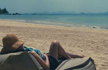 young woman lying on bean bag at beach to take sunbath on summer vacation