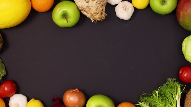 Vibrant frame made of fresh fruits and vegetables on black background. Stop motion