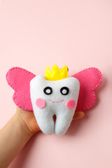 Cute toy for Tooth Fairy Day as funny smiling cartoon character of tooth fairy with crown, wings on pink background, copy space flyer, concept children milk toothless, funny toy, handmade felt diy