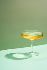 Wine Glass of white wine with bright shadows over green background
