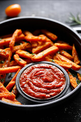 Close up of tomato sauce served with sweet potato fries on a cast iron dish 