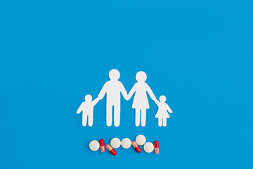 a paper figure of a family and medical pills on a blue background copy the space. the concept of health preservation, treatment of viral disease and influenza in a pandemic
