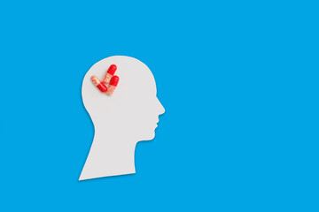 medical treatment of the human brain. paper figure of a human head and medical supplies on a blue background