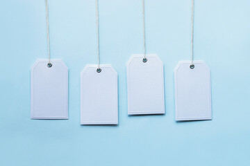 Four white blank tags on light blue background. Sales concept