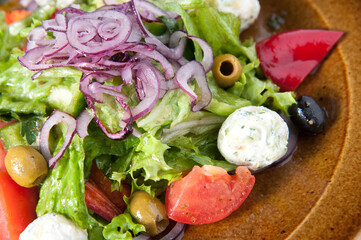 Greek salad. Fresh vegetables: tomatoes, olives, peppers, lettuce, onions on a plate, sliced ​​and poured with olive oil.