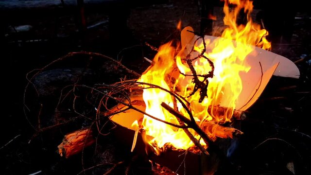 Fire in the cardboard box on dark background. Fireplace in the night forest. Inflammation flame in the safety bound
