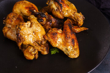 Close-up of grilled chicken wings and drumsticks on dark