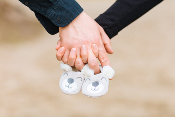 two hands hold the shoes of a baby. Concept of desire for children, pregnancy, love, family and...