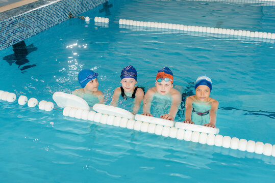 A group of boys and girls train and learn to swim in the pool with an instructor. Development of children's sports.