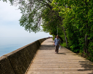 The Boardwalk on the Toronto's Centre Island with a lone male senior citizen walking it on a sunny spring day.