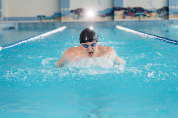 A young athlete trains and prepares for swimming competitions in the pool. Healthy lifestyle.