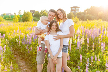 Happy family mother father embracing kids outdoor. Woman man baby child and teenage girl on summer field with blooming flowers background. Happy family mom dad and daughters playing on meadow.