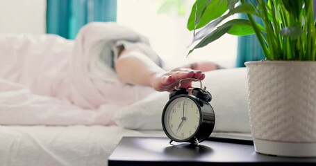 Woman sleeping on the bed turns off the alarm. Woman wakes up from the ringing alarm clock