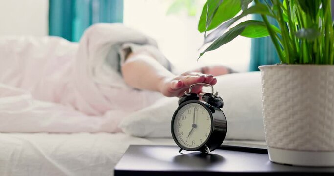 Woman sleeping on the bed turns off the alarm. Woman wakes up from the ringing alarm clock