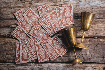 Tarot cards and golden goblets on the wooden flat flat lay background.