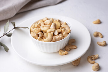 Raw nuts in a bowl on a white background, vegetarian food, raw eating.