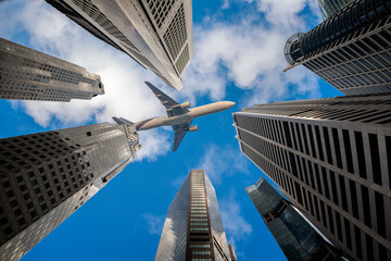 A low-angle view of Passenger planes flying past numerous commercial buildings and skyscrapers in the city center