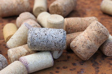 Wine cork from from semi-sweet wine, cork from white wine and cork from red wine among other corks on rusty background