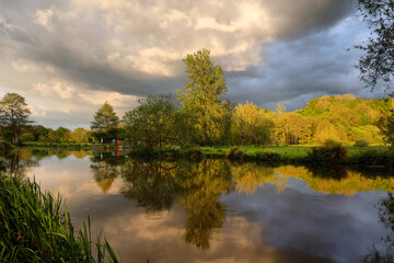 Fototapeta na wymiar Stormy skies and rain as the sun sets over the River Wey and meadows in Godalming, Surrey, UK
