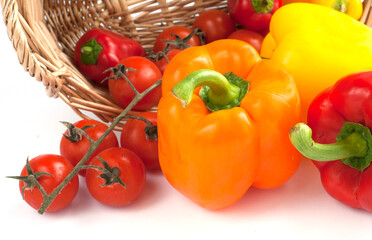 Orange, yellow and red peppers with cherry tomato in a basket on the white background. Wegetables in basket close-up.