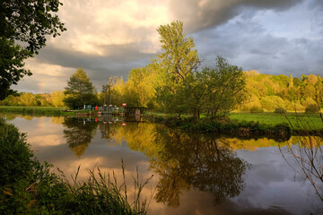 Stormy skies and rain as the sun sets over the River Wey and meadows in Godalming, Surrey, UK